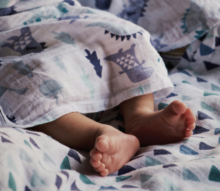 Baby resting beneath lightweight bedding