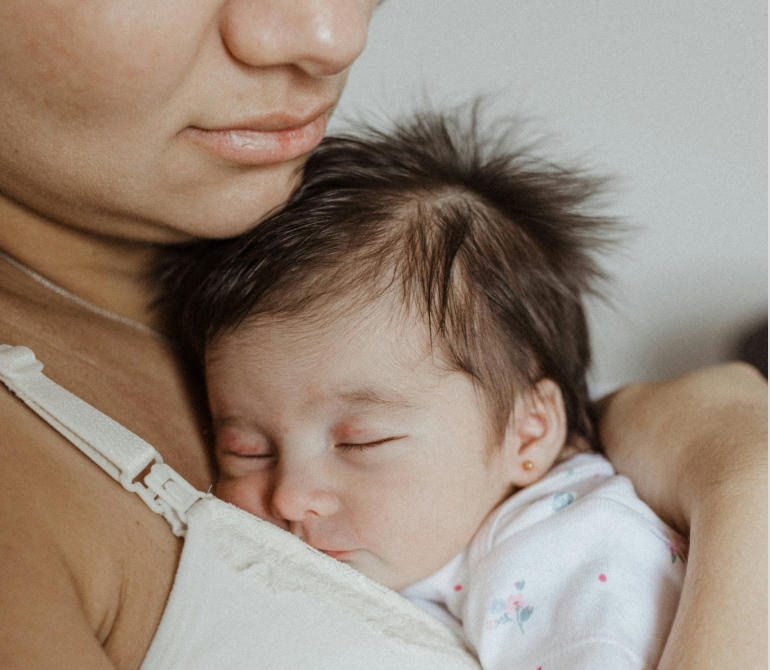 Sleeping baby resting against a parent